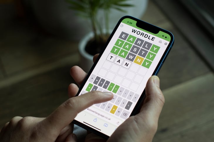 A woman plays Wordle on its official website on her iPhone.