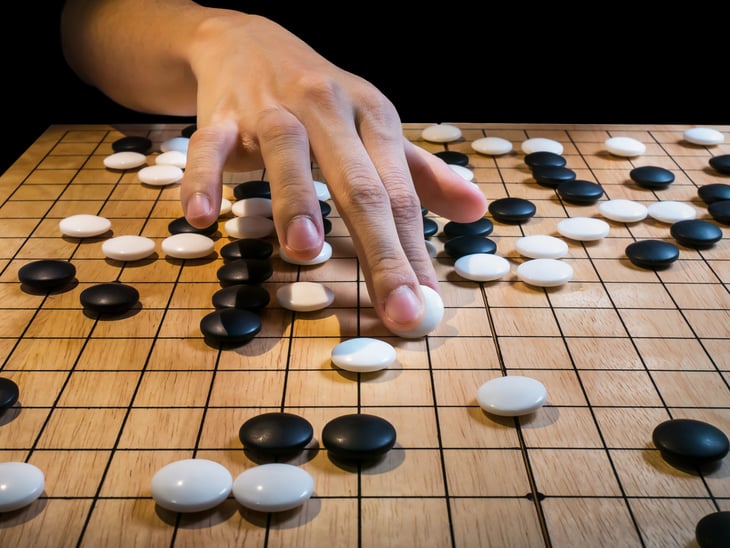 Player's hand making a move in a game of Go (Weiqi, Baduk). Traditional Asian strategy board game
