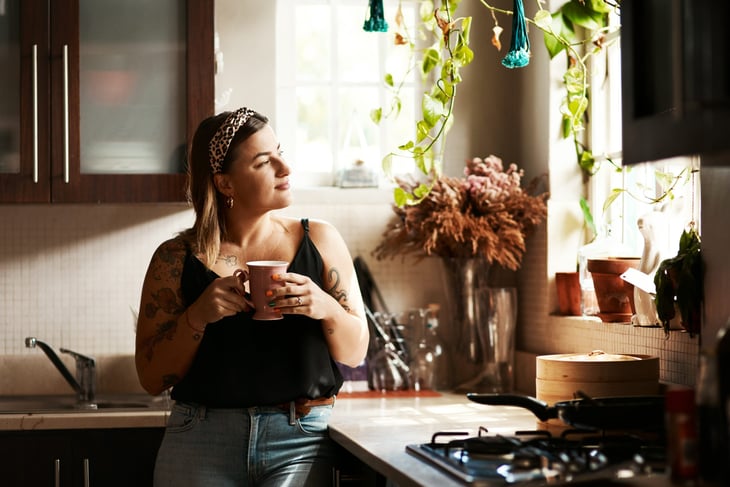 Woman in kitchen drinking coffee