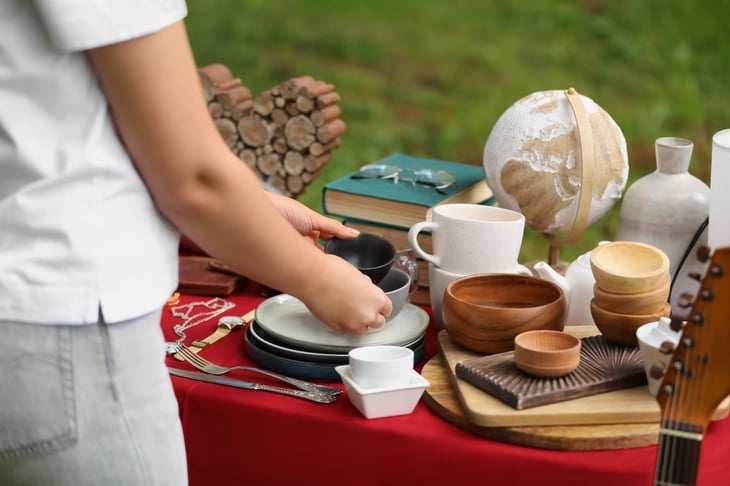 Woman looking at wooden bowls at a table at an estate sale.