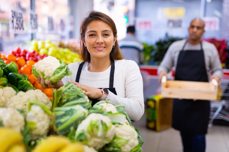 Grocery store worker holding cauliflower