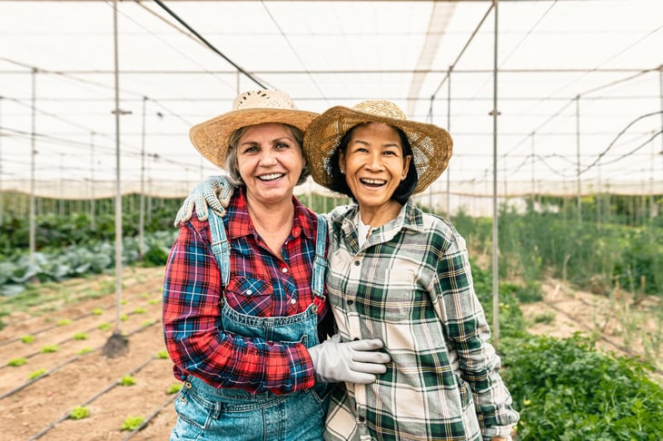 Happy women farmers smiling while working inside a greenhouse.
