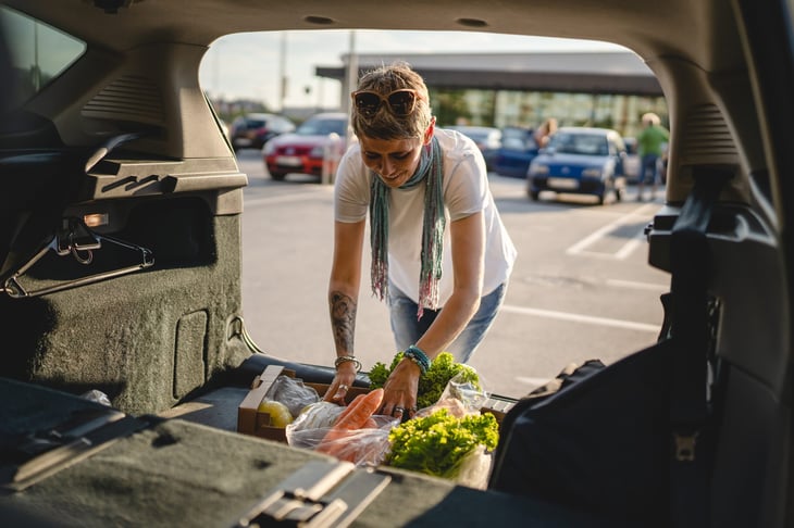 Shopper putting groceries in a car trunk