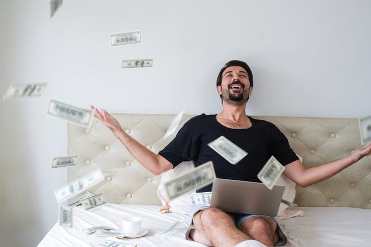 Man in bed with money raining down