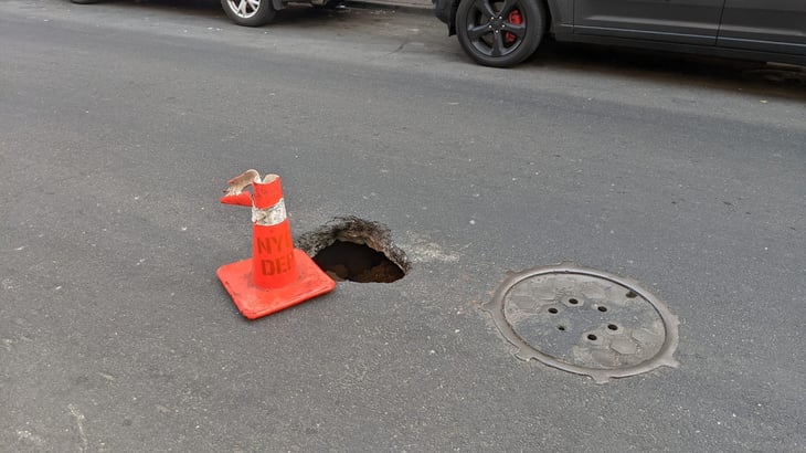 A sinkhole in the street with a traffic cone in Queens, New York, 2024.