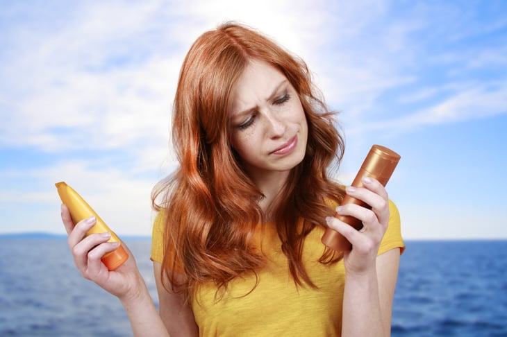 Woman looking at two different sunscreen products