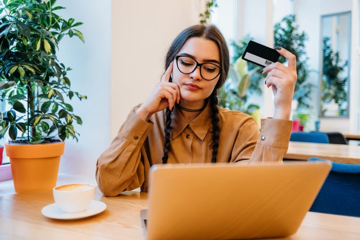 Woman at a laptop holding a credit card.