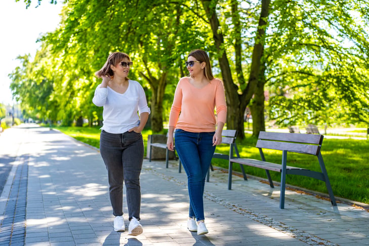 A couple of women talking while taking a walk in the park.