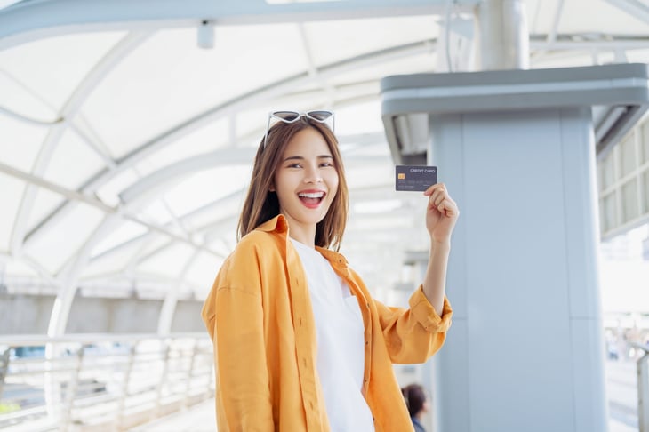 Happy female traveler holding up a credit card in an airport