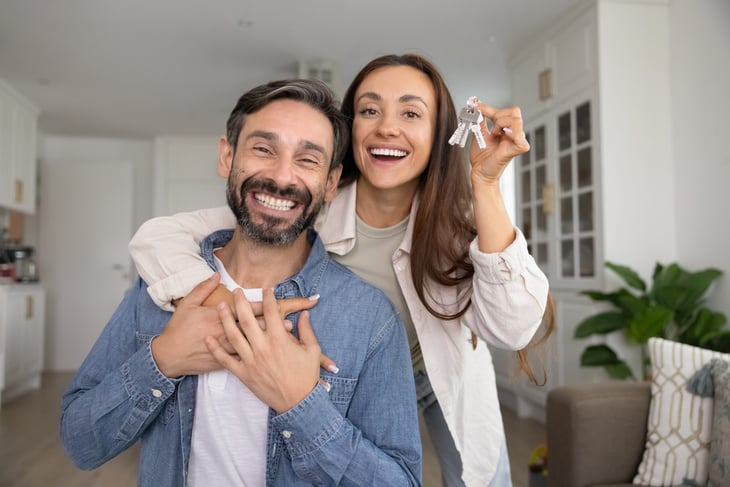 Happy homeowner couple holding up house keys