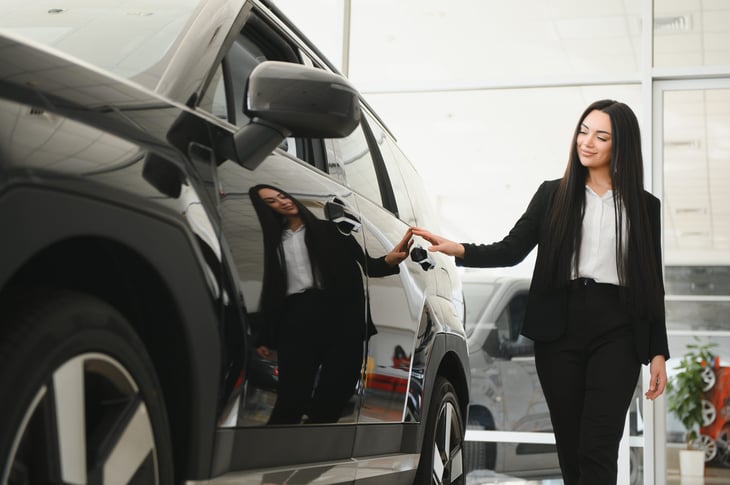 Woman with brand new car at a car dealership.