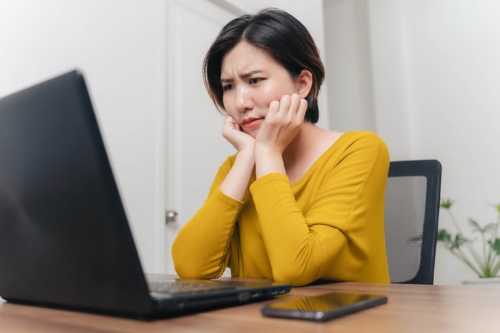 Young woman looking concerned at her laptop