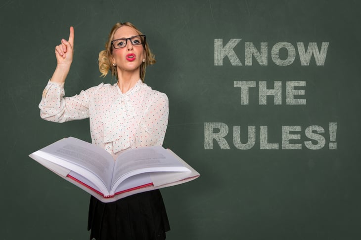 Woman with book in front of a chalkboard that says Know the Rules!