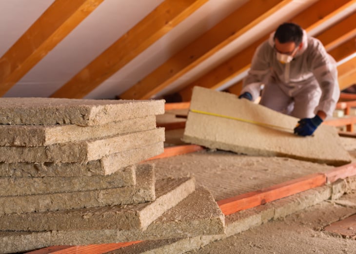 Man adding insulation to an attic