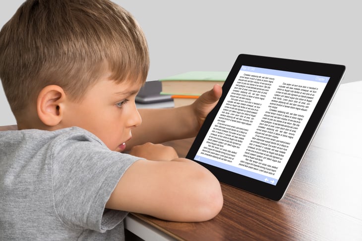 A young boy reads on a tablet