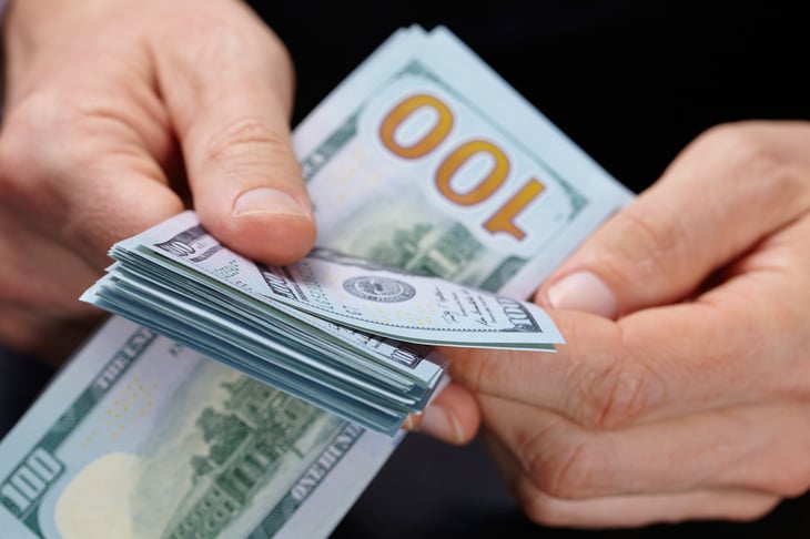 Hands counting US $100 bills