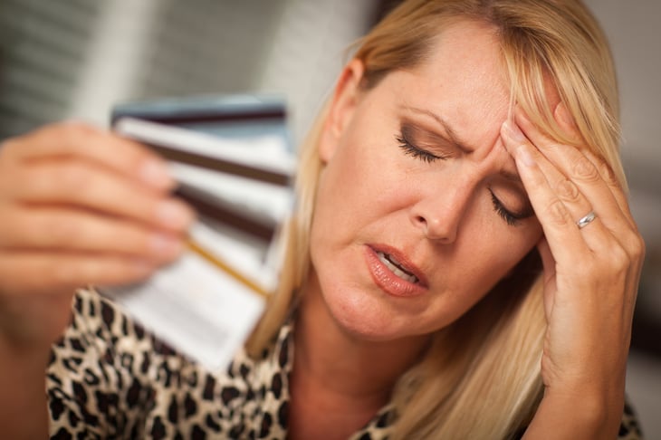 Depressed-looking woman with hand full of credit cards.