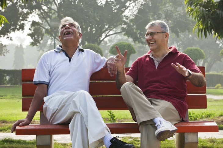 Two men talk and laugh on a park bench
