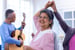 Joyful senior woman dancing at a happy musical event with a senior playing guitar indoors at home